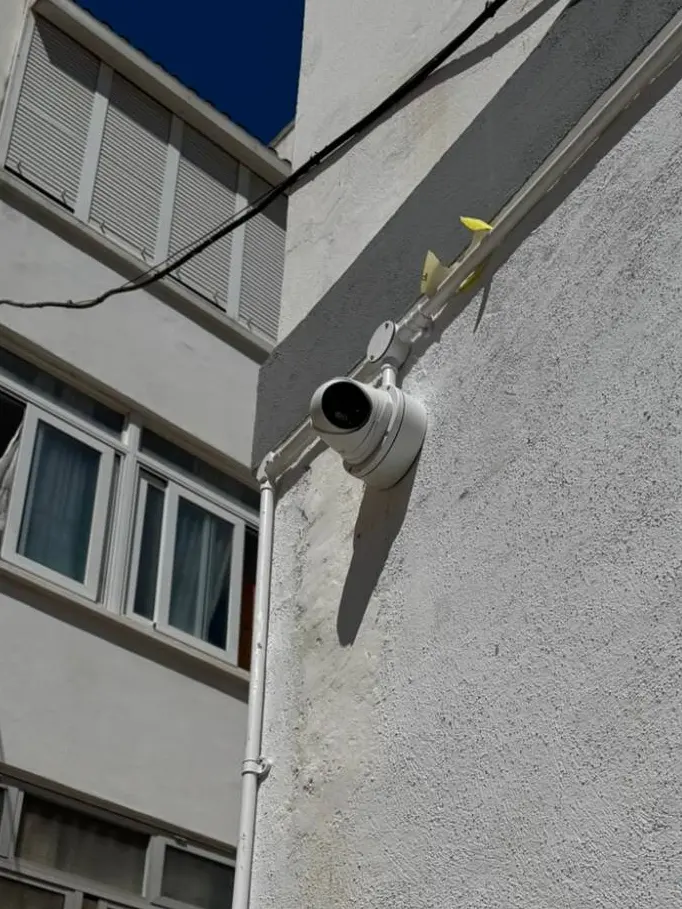 Turret camera mounted on a rear elevation with conduit run alongside existing pipework