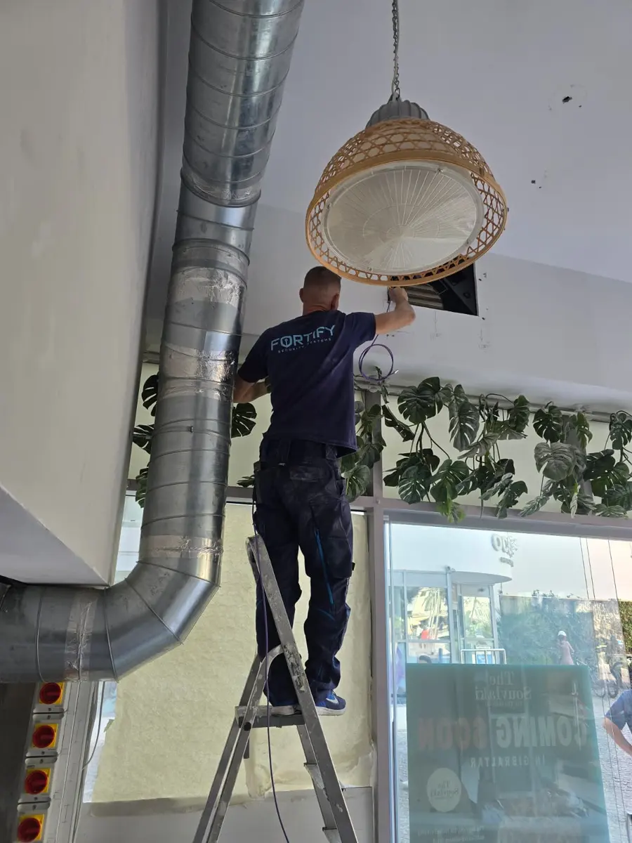 Fortify engineer on a ladder installing security cabling in a commercial unit in Gibraltar